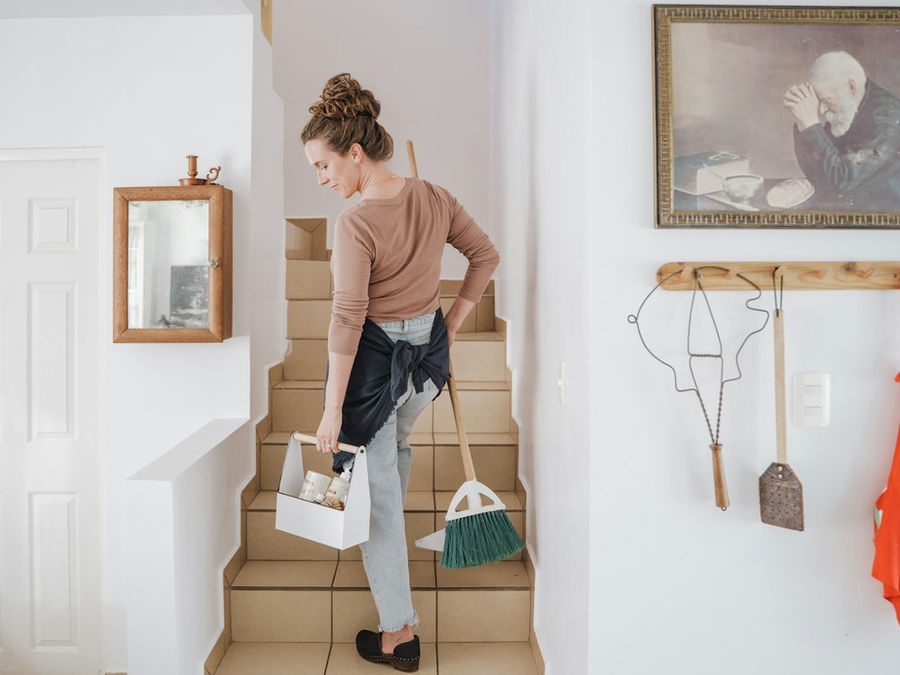 Reinigungskraft mit Putzmitteln auf der Treppe